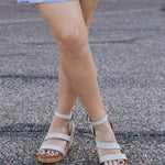 Person wearing sparkly sandals on a pavement background