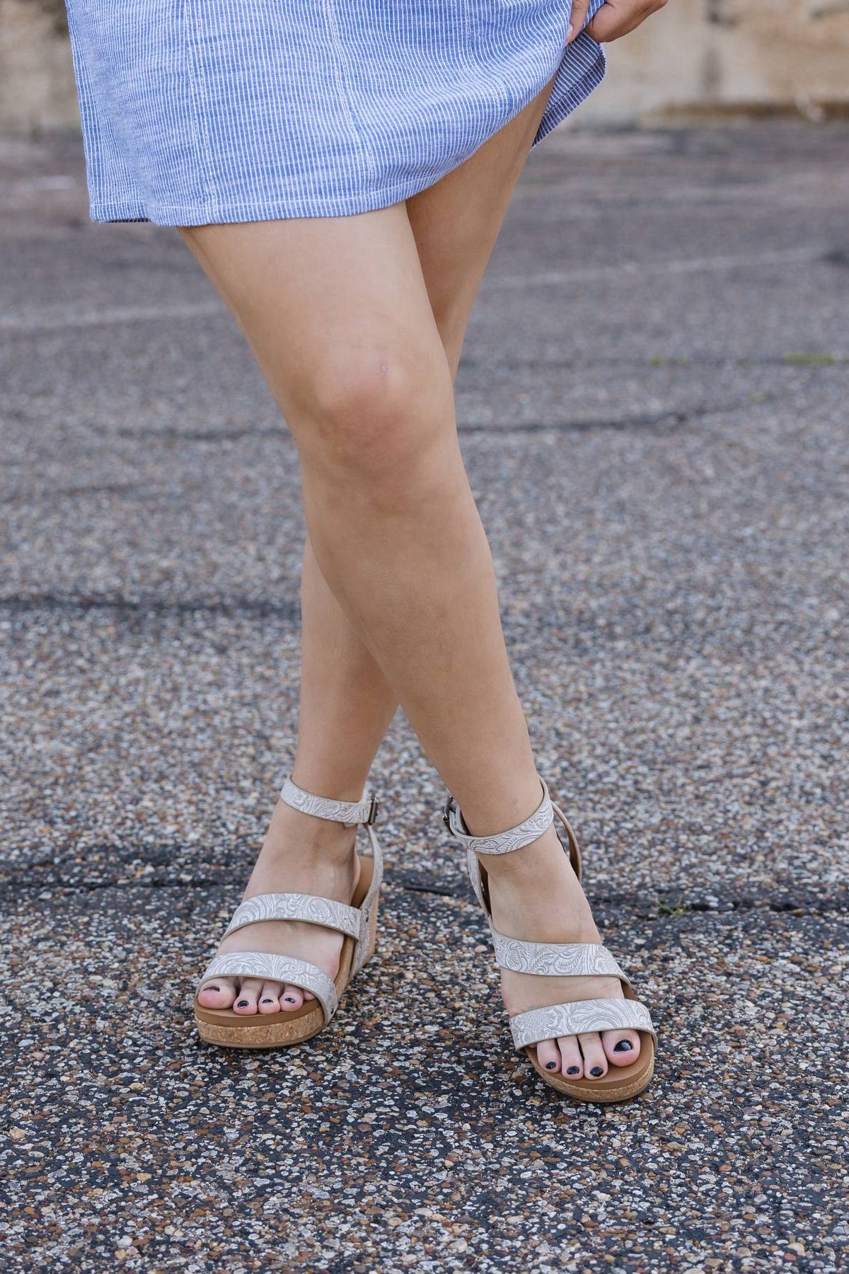 Person wearing sparkly sandals on a pavement background