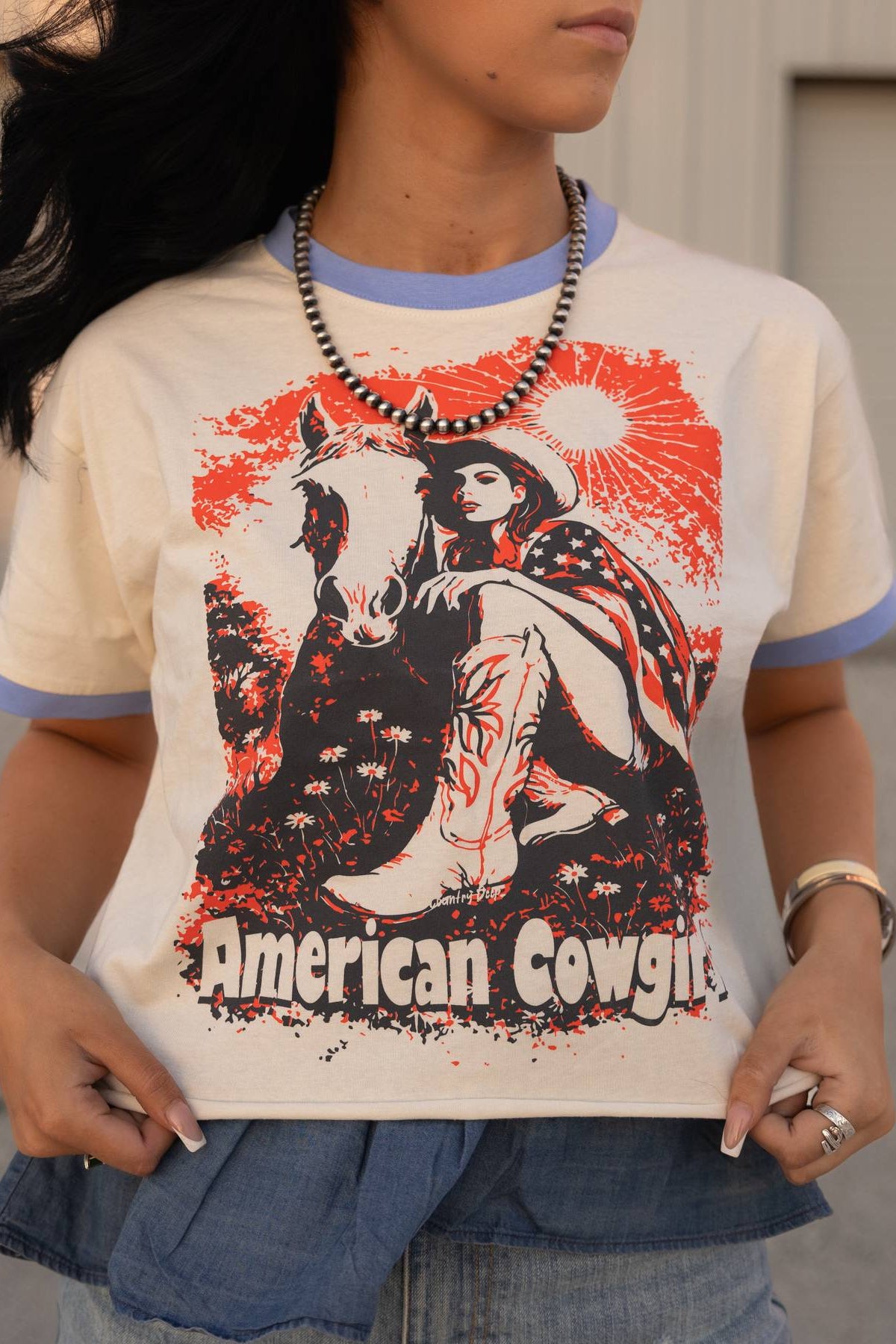 Person wearing a t-shirt with an 'American Cowgirl' graphic design.
